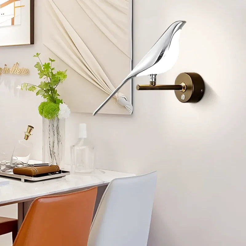 Applique murale Luminaire Essenza avec interrupteur LED rotatif 360°, design oiseau en double or et blanc naturel.