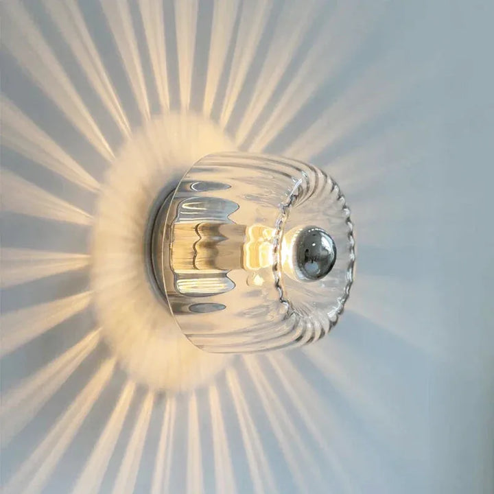 Applique murale en verre Luminaire Essenza avec effet soleil, finition chrome et lumière blanc chaud, moderne et élégante.