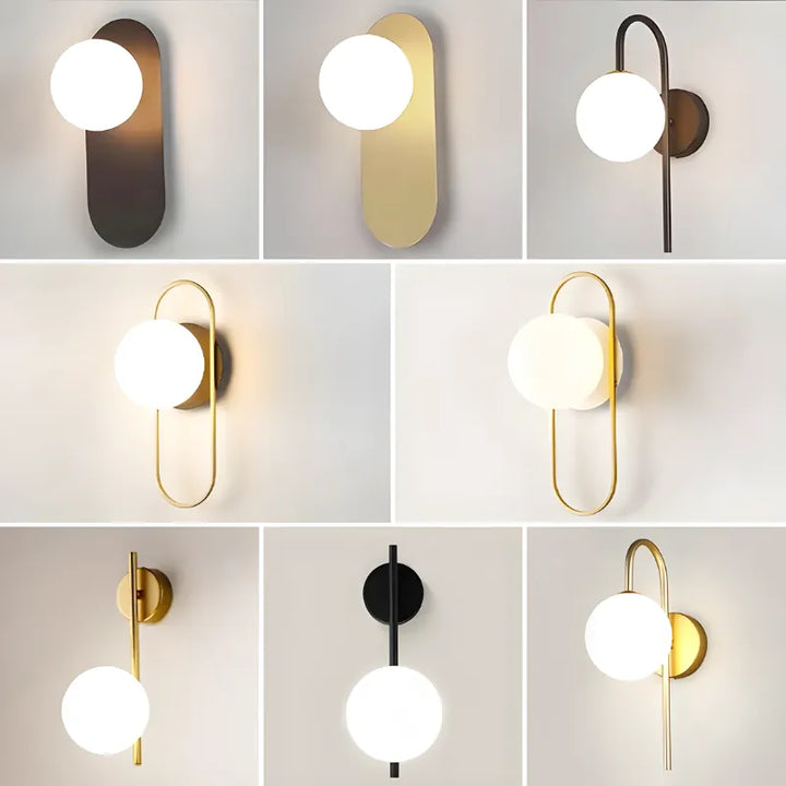 Applique murale LED décorative en boule Luminaire Essenza avec finition or et lumière blanche froide sur un mur blanc.