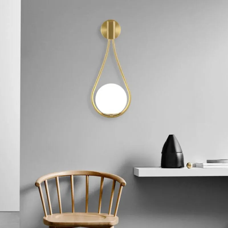 Applique murale LED en verre avec sphère suspendue, finition or blanc chaud, éclairage moderne pour intérieur.