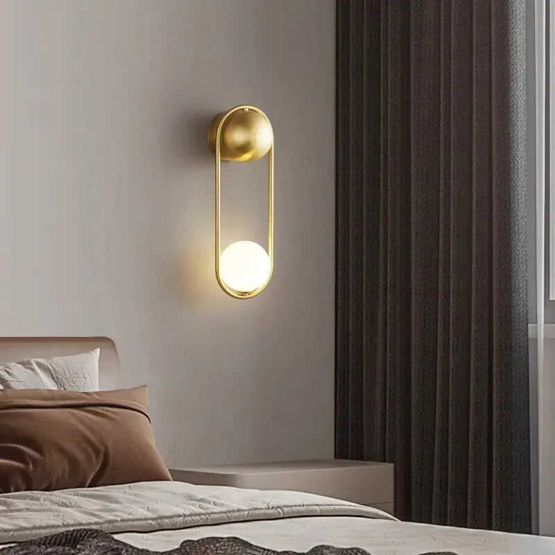Applique murale LED minimaliste Luminaire Essenza avec boule suspendue, finition dorée et lumière blanc chaud 2700-3500K.